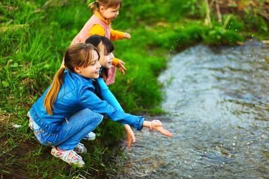 Children playing beside a stream